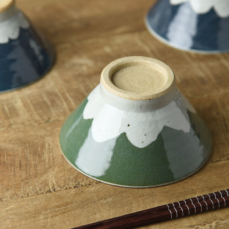 A green Mt. Fuji rice bowl turned upside down on a wooden table